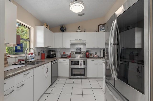 kitchen featuring backsplash, white cabinets, stainless steel appliances, and lofted ceiling