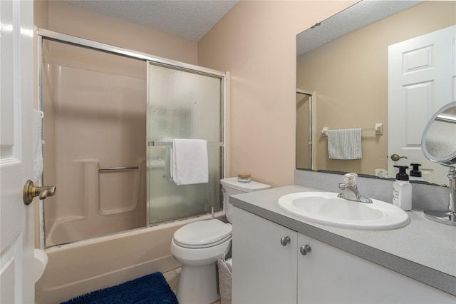 full bathroom featuring toilet, vanity, a textured ceiling, and combined bath / shower with glass door