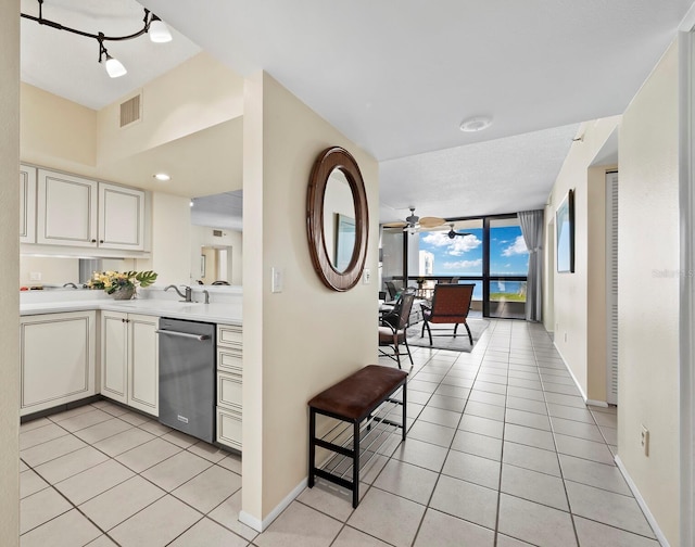 kitchen with dishwasher, ceiling fan, expansive windows, and light tile patterned flooring