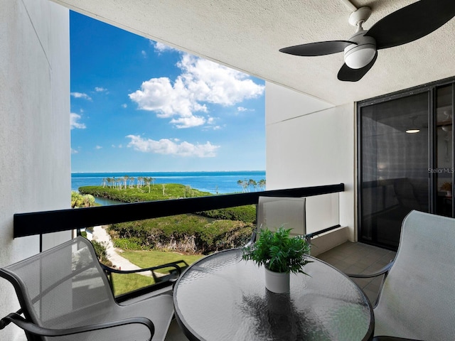 balcony with ceiling fan and a water view