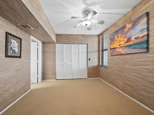 unfurnished bedroom featuring ceiling fan, carpet floors, and a textured ceiling