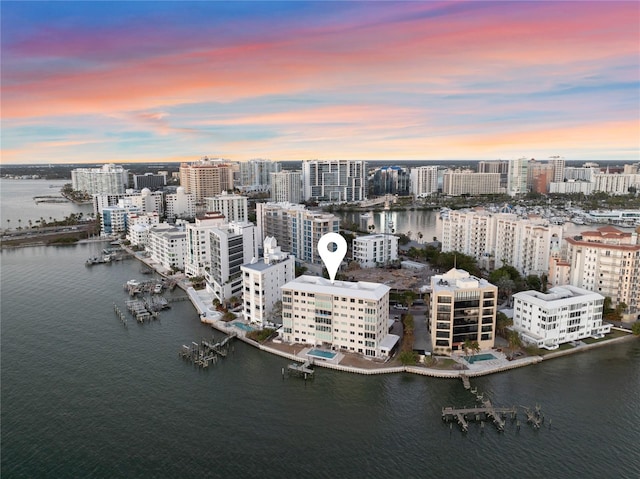 aerial view at dusk featuring a city view and a water view