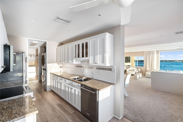 kitchen featuring tasteful backsplash, stainless steel dishwasher, sink, a water view, and white cabinets