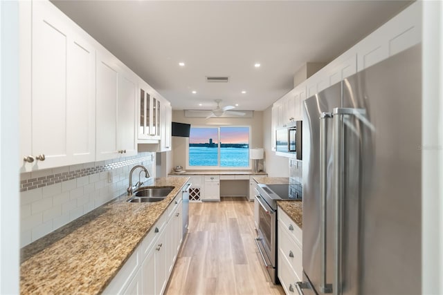 kitchen featuring white cabinetry, sink, light stone countertops, and appliances with stainless steel finishes