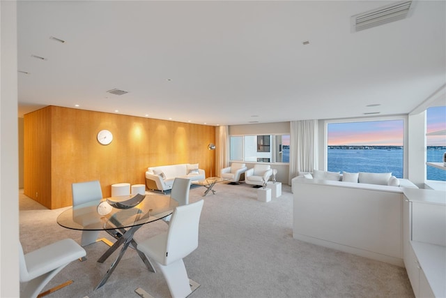 dining area featuring a water view and light colored carpet