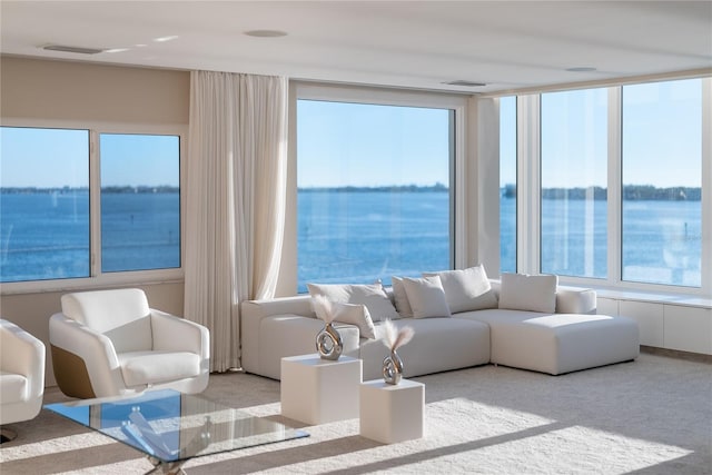 living room featuring a water view, a healthy amount of sunlight, and light colored carpet