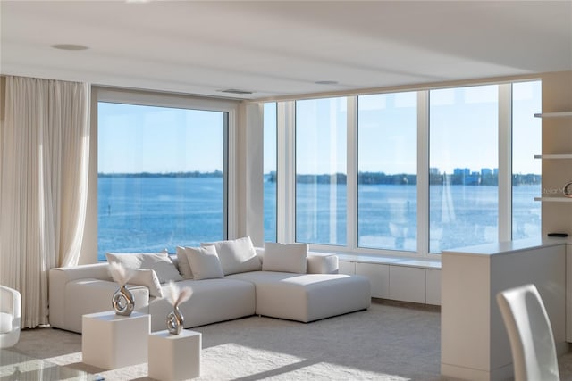 living room featuring plenty of natural light, a water view, and light carpet