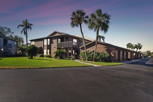 view of front of home featuring a balcony and a yard