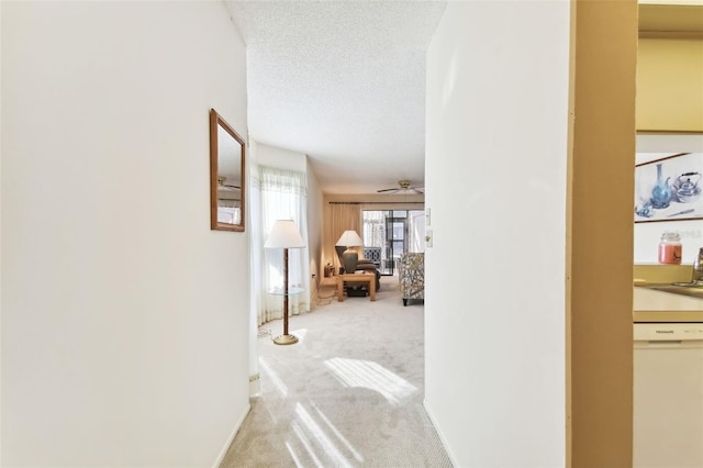 corridor featuring a textured ceiling and light colored carpet