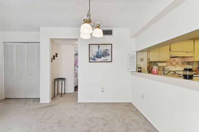 unfurnished dining area featuring a textured ceiling, light carpet, and a chandelier