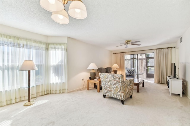 living room featuring ceiling fan, light colored carpet, and a textured ceiling