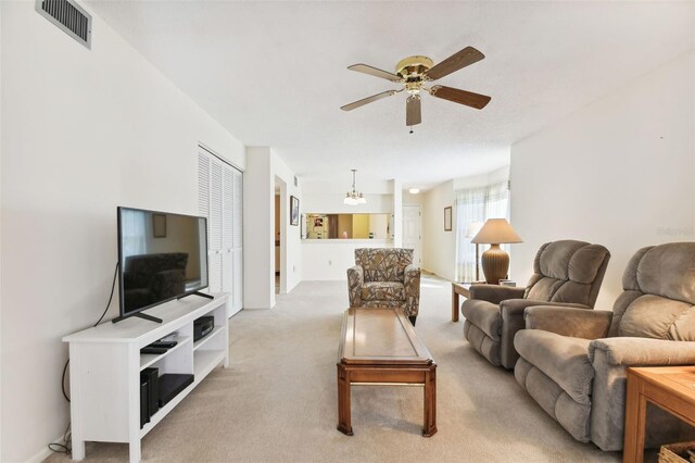 living room with ceiling fan with notable chandelier and light colored carpet