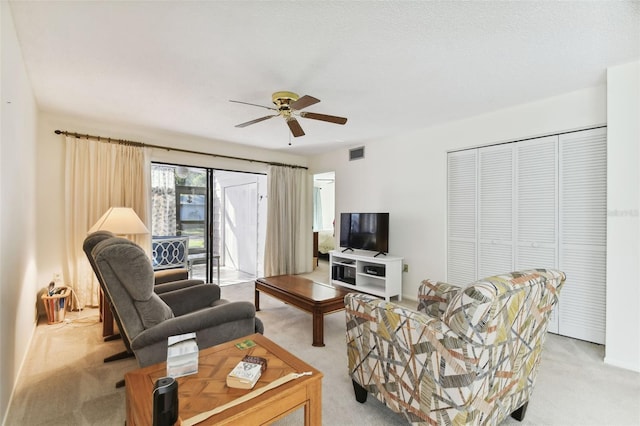 carpeted living room featuring a textured ceiling and ceiling fan