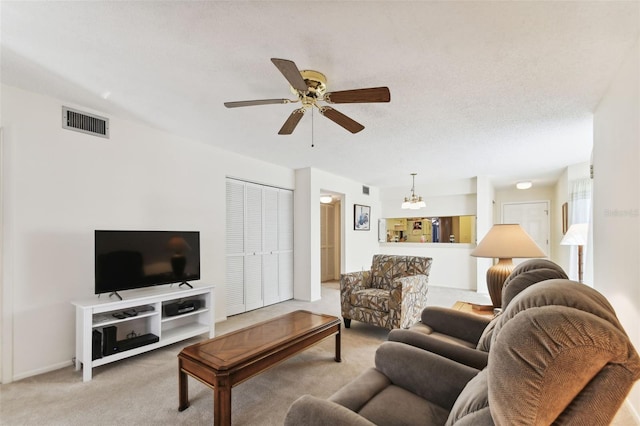 carpeted living room with ceiling fan with notable chandelier and a textured ceiling