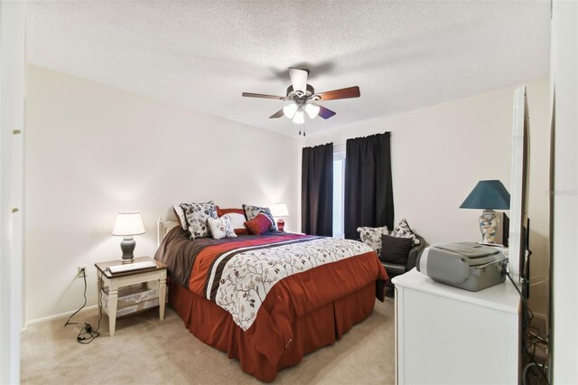 bedroom with ceiling fan, light colored carpet, and a textured ceiling