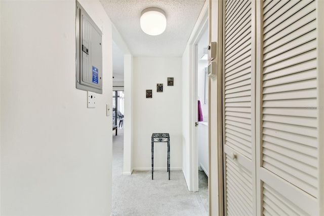 hallway featuring electric panel, light colored carpet, and a textured ceiling