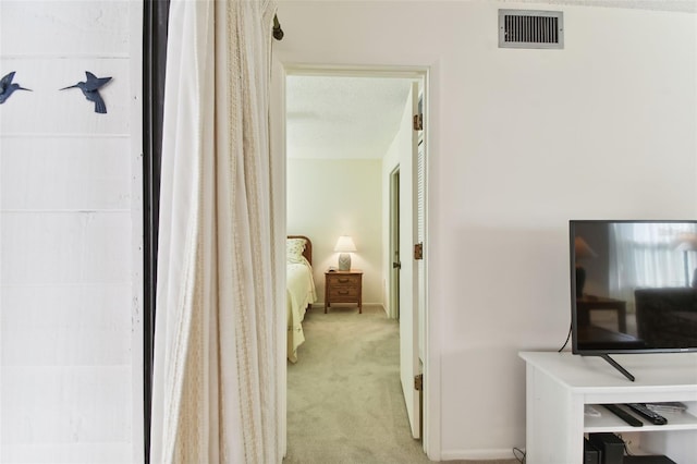 hallway with light carpet and a textured ceiling