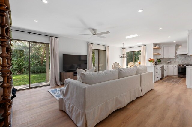 living room featuring sink, light hardwood / wood-style floors, plenty of natural light, and ceiling fan