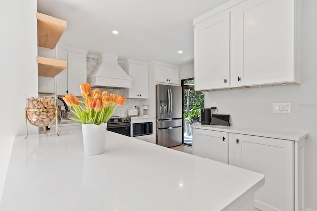 kitchen with white cabinets, custom range hood, backsplash, and stainless steel appliances