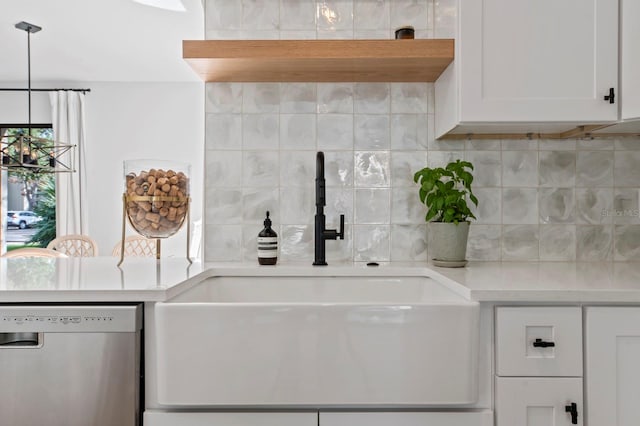 kitchen featuring tasteful backsplash, stainless steel dishwasher, sink, white cabinetry, and hanging light fixtures