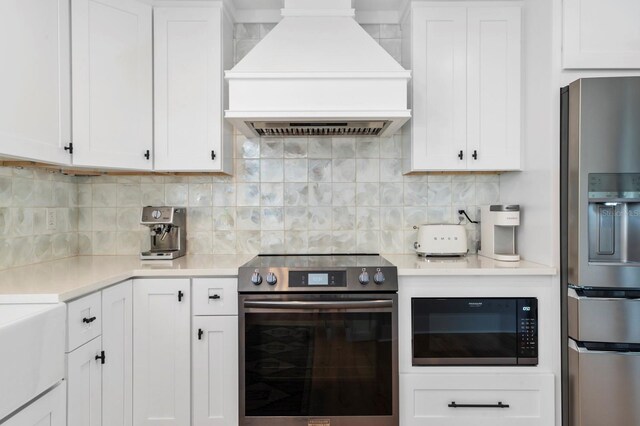 kitchen with tasteful backsplash, white cabinetry, custom exhaust hood, and appliances with stainless steel finishes