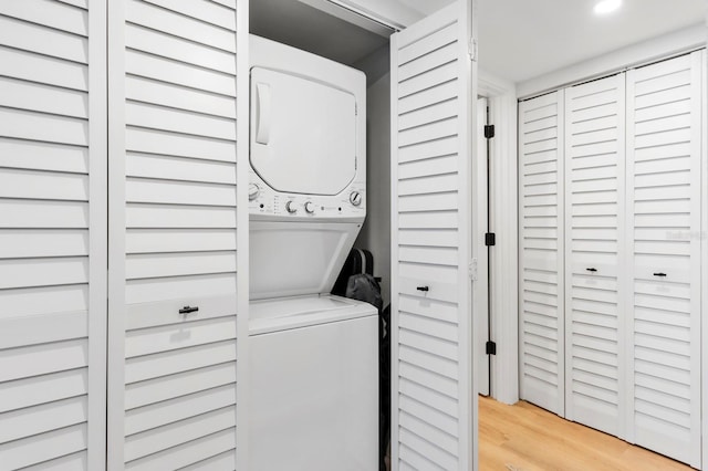 washroom with light wood-type flooring and stacked washer and clothes dryer