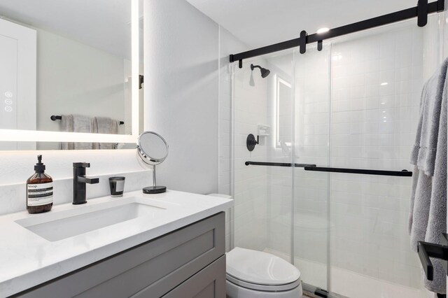 bathroom featuring vanity, an enclosed shower, and toilet