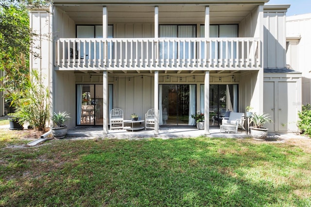 rear view of house featuring a patio, a balcony, and a lawn