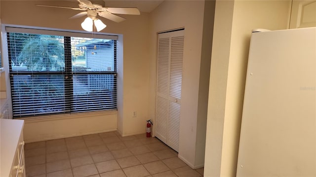 unfurnished bedroom featuring ceiling fan, white refrigerator, light tile patterned floors, and a closet