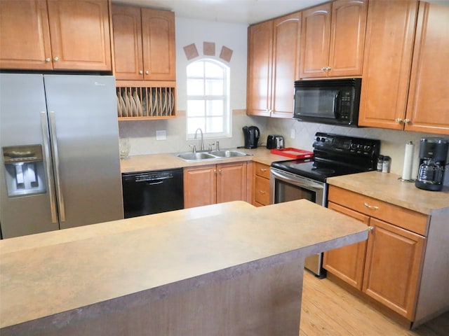 kitchen featuring light countertops, a sink, backsplash, and black appliances