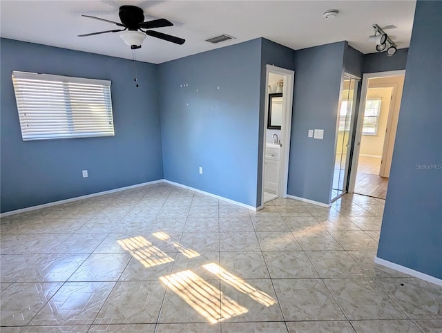 unfurnished room featuring ceiling fan, light tile patterned floors, visible vents, and baseboards