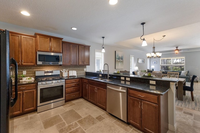 kitchen featuring kitchen peninsula, appliances with stainless steel finishes, hanging light fixtures, and sink