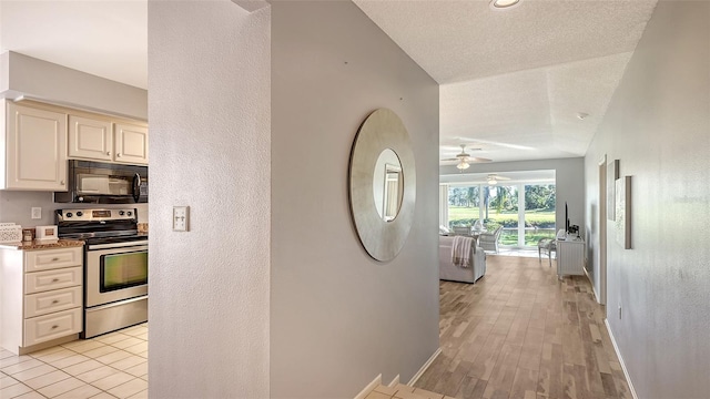 corridor with light hardwood / wood-style floors and a textured ceiling