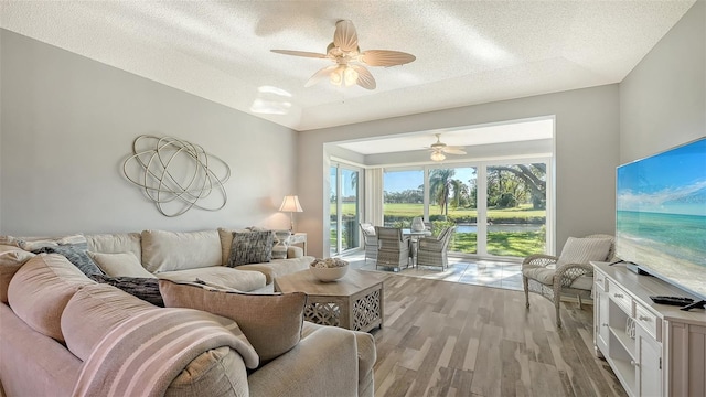 living room with a textured ceiling, light hardwood / wood-style floors, and ceiling fan