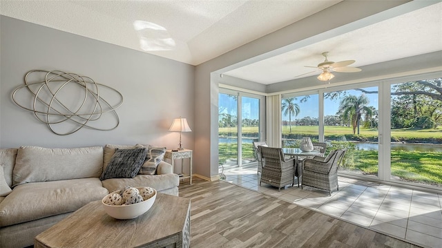 living room with a water view, light hardwood / wood-style flooring, plenty of natural light, and ceiling fan