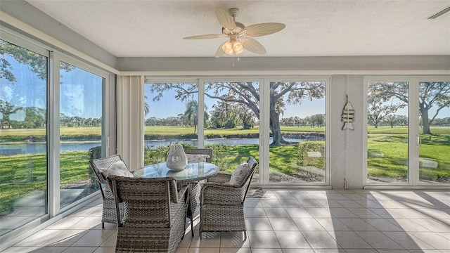 sunroom featuring ceiling fan, a healthy amount of sunlight, and a water view