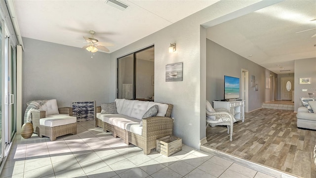 living room featuring a textured ceiling, light hardwood / wood-style floors, and ceiling fan