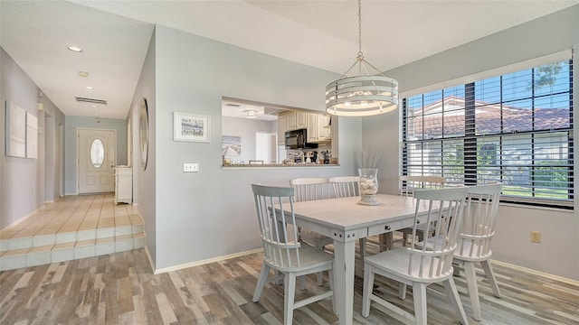 dining room featuring a chandelier, light hardwood / wood-style floors, and a textured ceiling