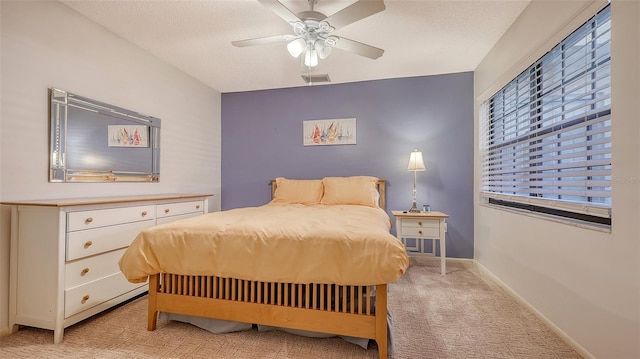 carpeted bedroom with ceiling fan and a textured ceiling