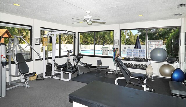 gym featuring a textured ceiling, ceiling fan, and a healthy amount of sunlight