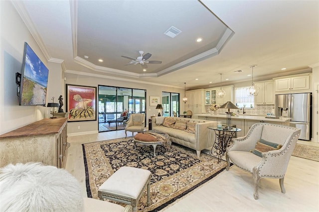 living room with plenty of natural light, ceiling fan, light wood-type flooring, and ornamental molding