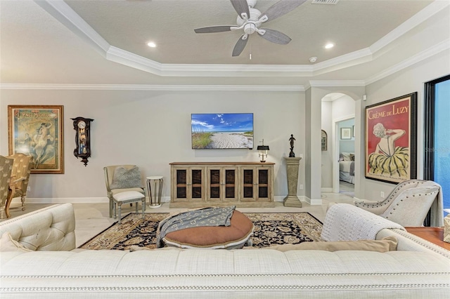 living room with ceiling fan, ornamental molding, and a tray ceiling