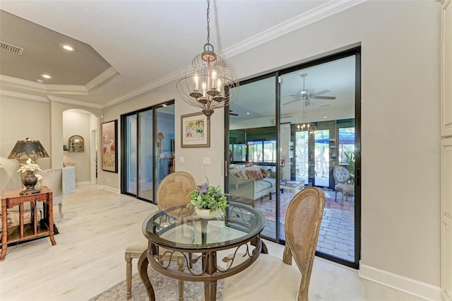 dining space with ceiling fan with notable chandelier, light hardwood / wood-style floors, a raised ceiling, and ornamental molding