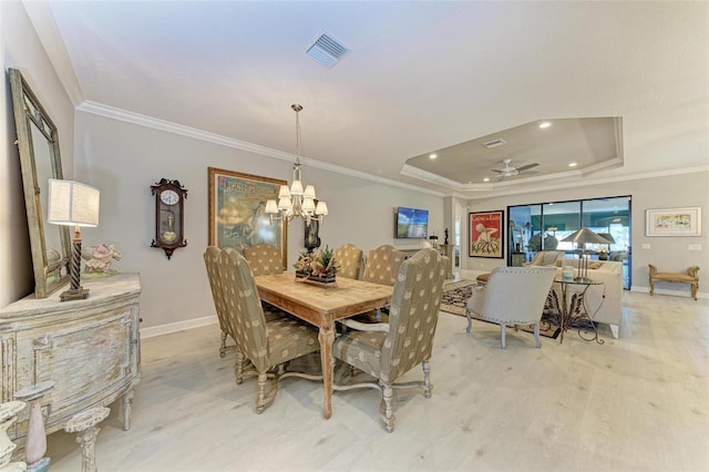 dining area featuring ceiling fan with notable chandelier, light hardwood / wood-style floors, crown molding, and a tray ceiling