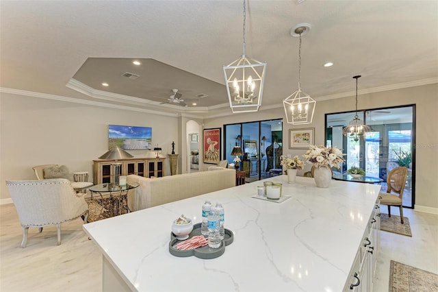 kitchen with white cabinetry, ceiling fan, light stone counters, and decorative light fixtures