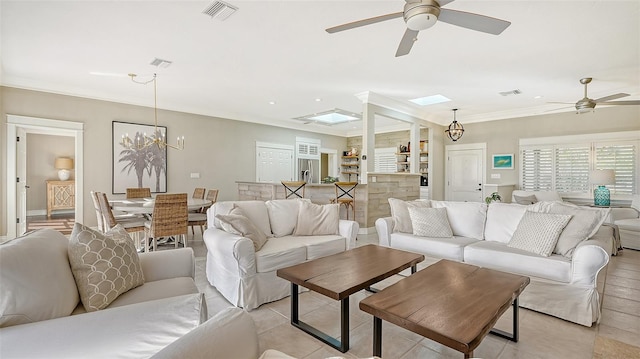 living room featuring a skylight and ceiling fan with notable chandelier