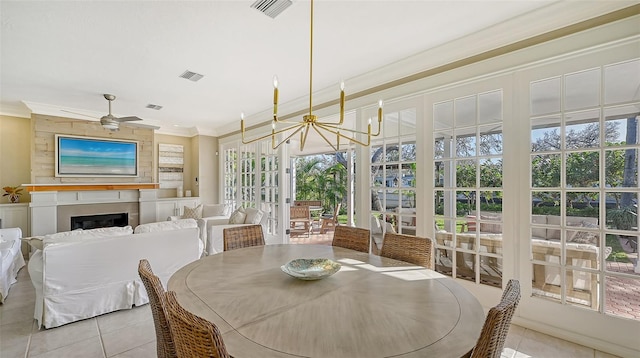 sunroom / solarium featuring a fireplace, ceiling fan with notable chandelier, and a wealth of natural light