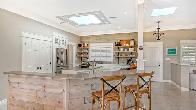 bar featuring a skylight, stainless steel fridge with ice dispenser, ornamental molding, light tile patterned flooring, and white cabinetry