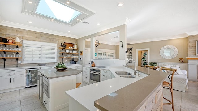 kitchen with sink, wine cooler, kitchen peninsula, oven, and a breakfast bar area