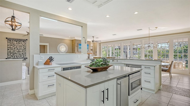 kitchen featuring a center island, crown molding, white cabinetry, and hanging light fixtures